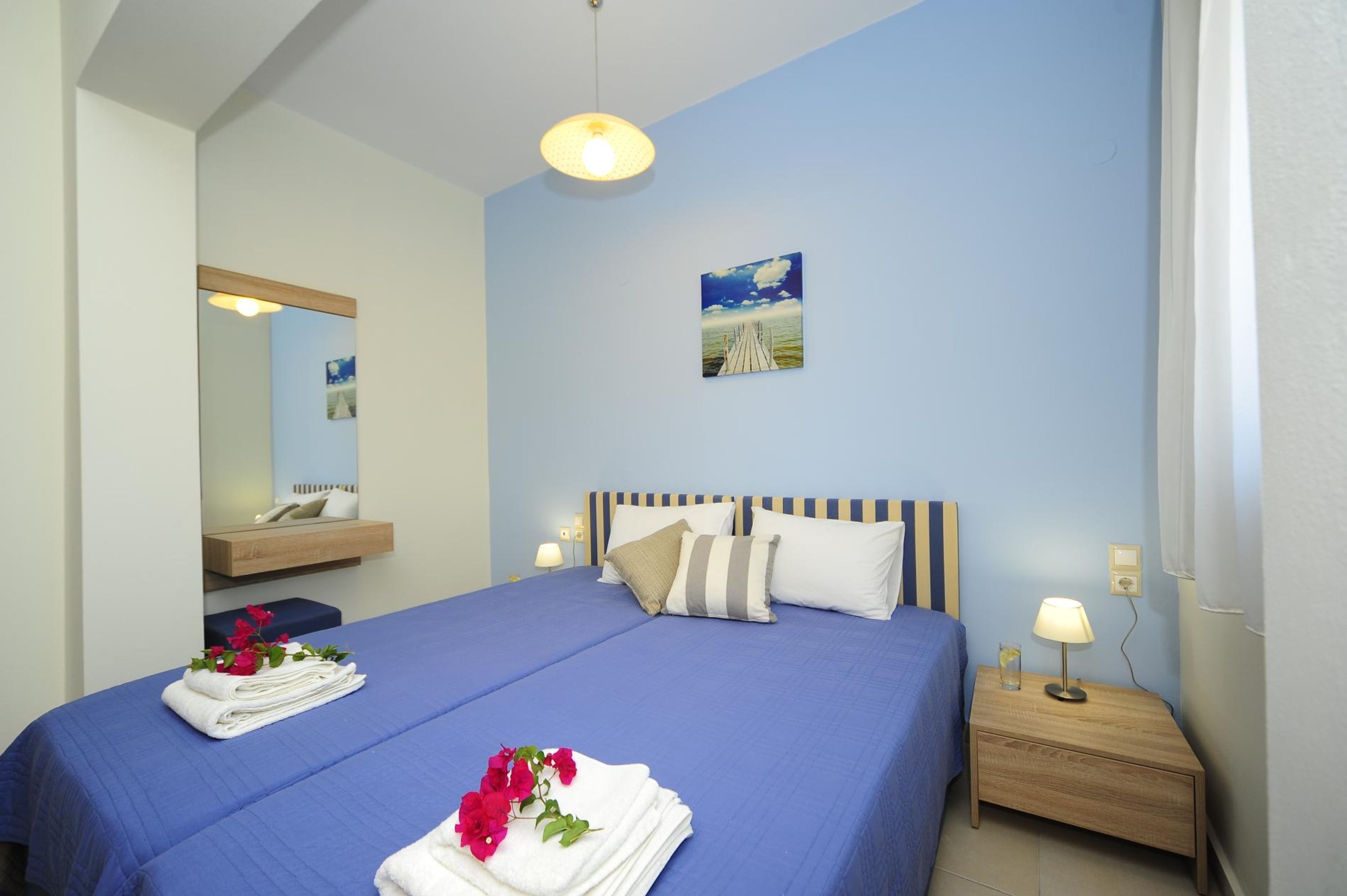 A bedroom with a bed, bedside table, lamp, and artwork on the wall.