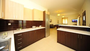A modern kitchen with dark wooden cabinets, a stainless steel refrigerator, and a white countertop. - Villa Orsalia With Private Pool (Rethymno)
