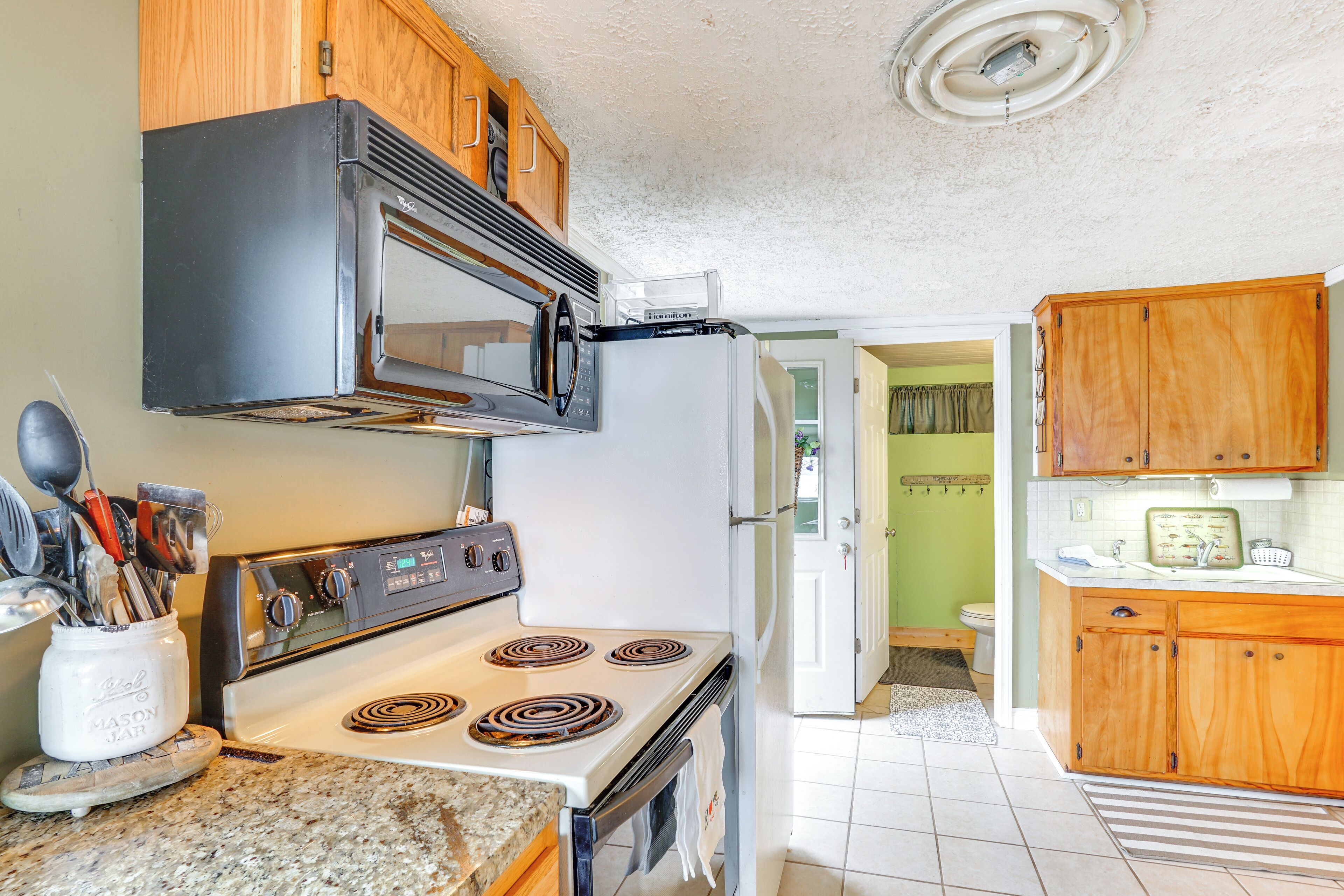 A kitchen with wooden cabinets, a stove, a microwave, and a refrigerator.