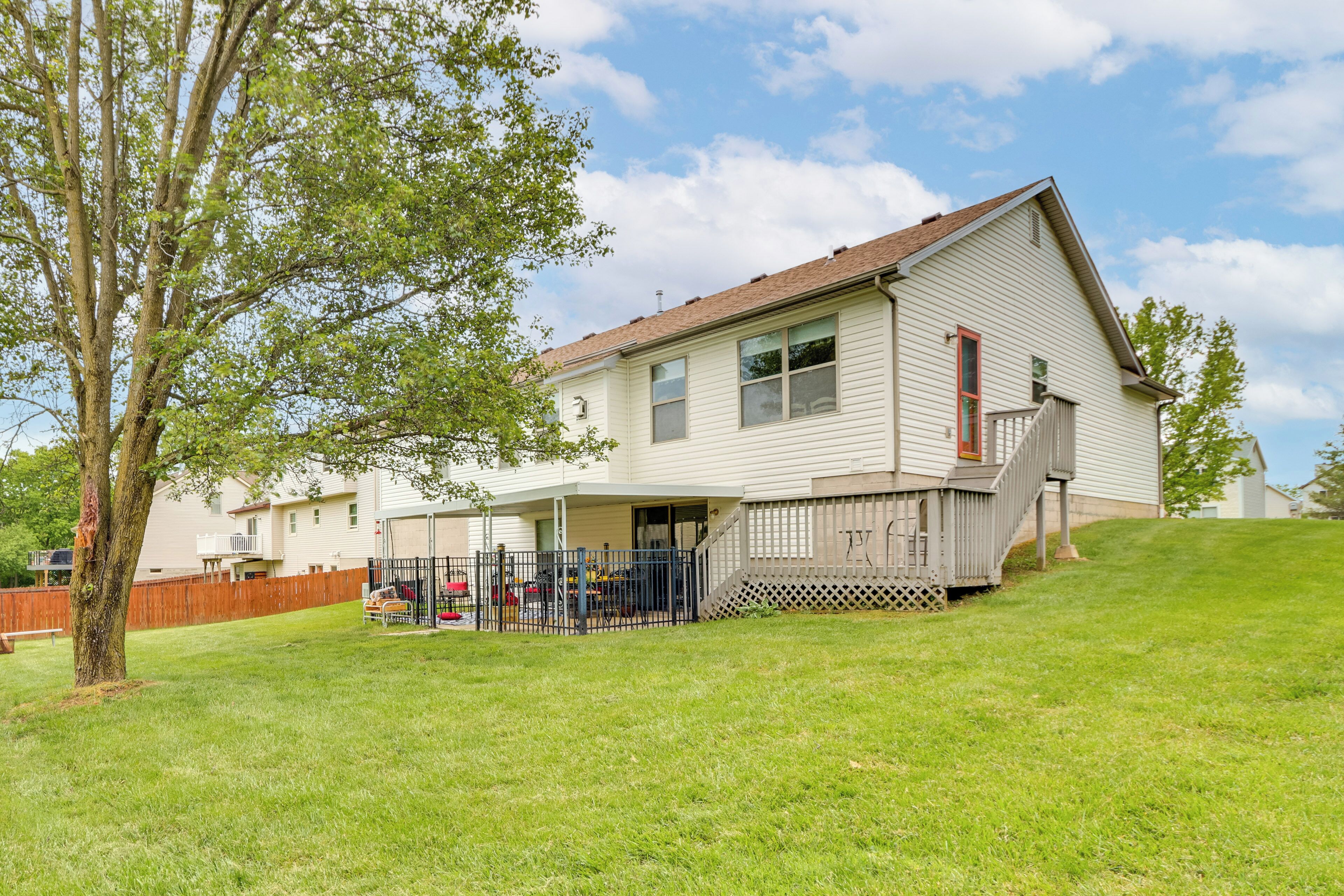 A two-story house with a covered porch and a fenced backyard.