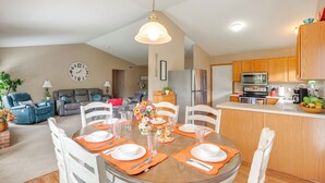 A dining area with a round table set for four, surrounded by white chairs. There is a kitchen area with wooden cabinets and a refrigerator in the background. - 17 Mi to Columbus: Pickerington Home w/ Fire Pit! (Pickerington)