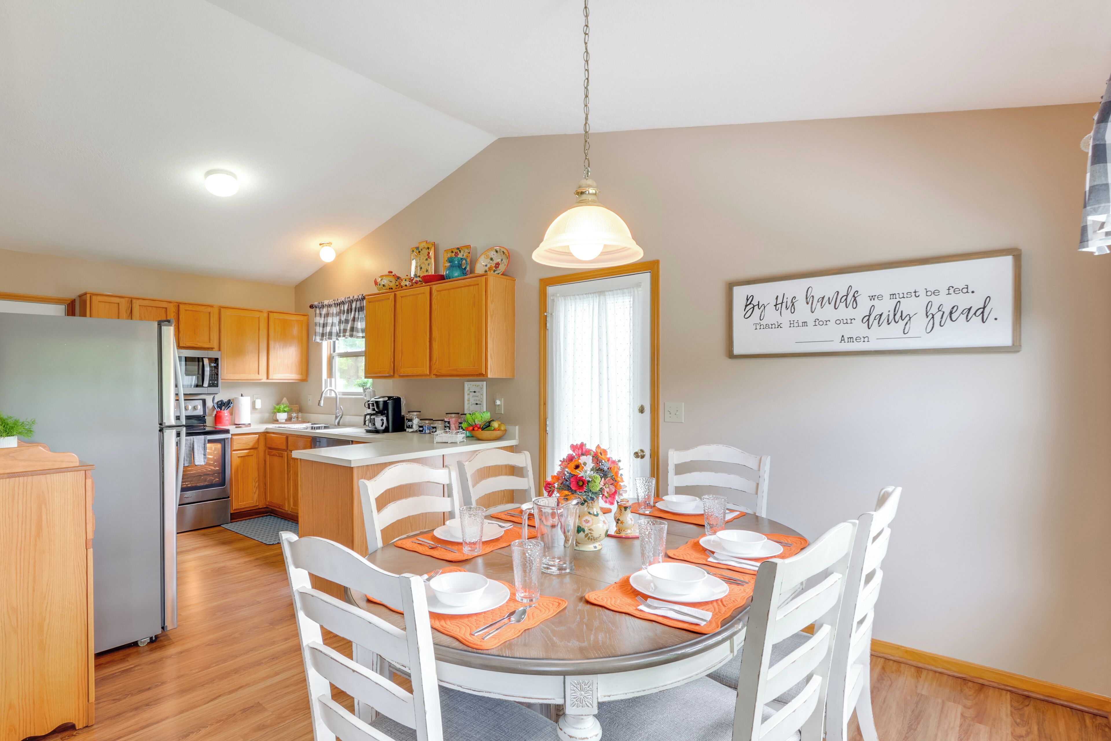 A modern kitchen with wooden cabinets, a dining table set for four, and a kitchen island.