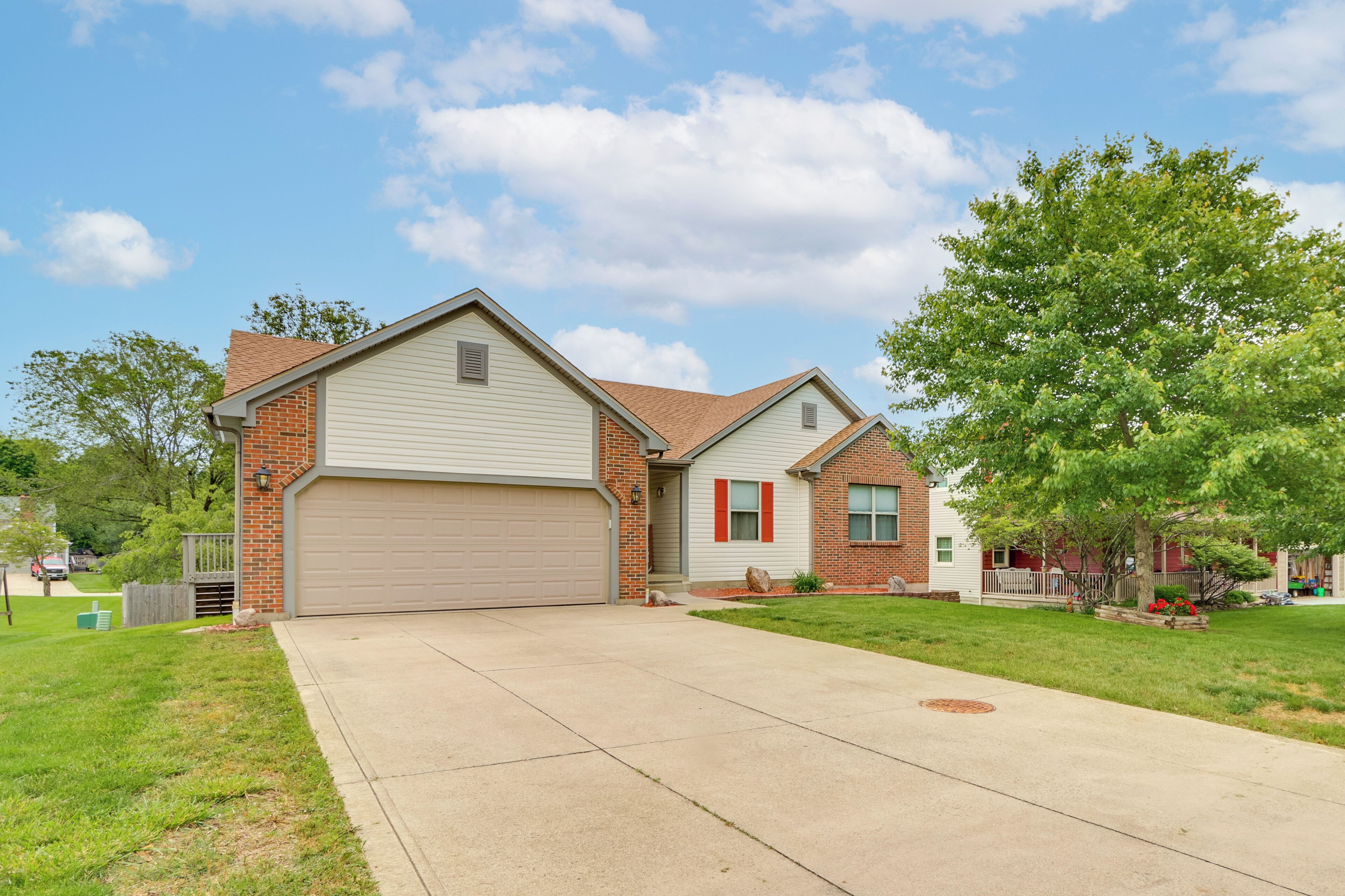 A two-story house with a garage, a front lawn, and a tree.