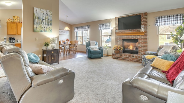 A living room with leather sofas, a fireplace, and a dining area with wooden cabinets and a coffee maker. - 17 Mi to Columbus: Pickerington Home w/ Fire Pit! (Pickerington)