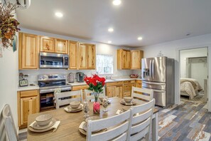 A modern kitchen with wooden cabinets, stainless steel appliances, and a dining table set for four. - Near Ocean: 'home Away From Home' in Gold Beach (Gold Beach)