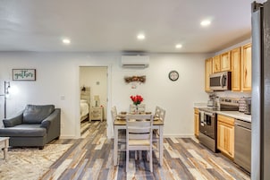 Una cocina compacta con armarios de madera, una mesa de comedor con sillas y un sofá de cuero gris.