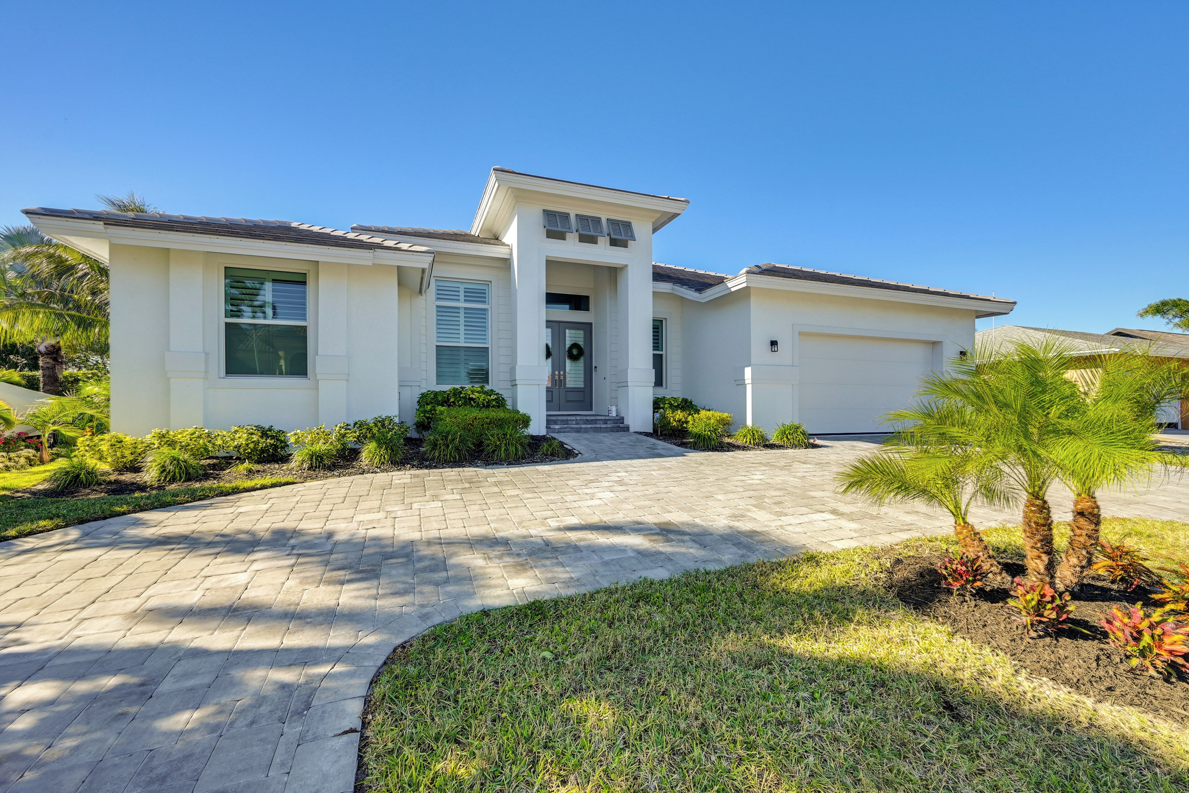 A modern two-story house with a paved driveway, a front porch, and a well-maintained lawn.