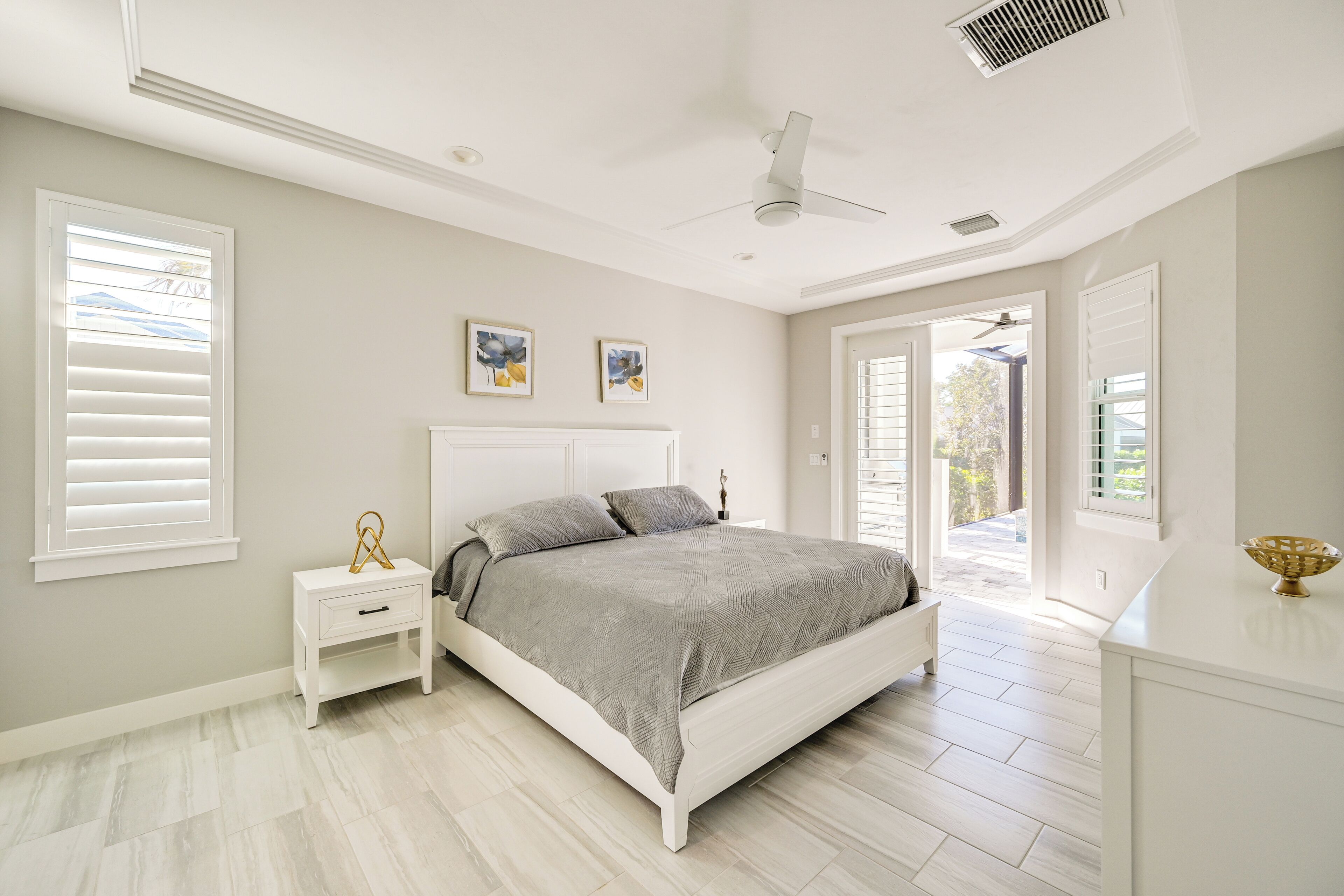 A bedroom with a bed, nightstand, and a view to the outside.