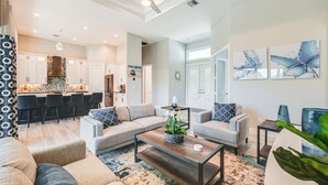 A modern living room with a sofa, armchairs, a coffee table, and a kitchen area in the background. - Luxury Marco Island Escape W/pool & Spa Retreat (Marco Island)