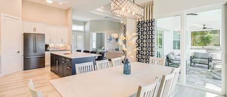 A spacious kitchen with a central island, white cabinetry, and a modern ceiling fan.
