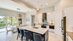 A modern kitchen with a large island, white cabinetry, and a built-in oven. - Luxury Marco Island Escape W/pool & Spa Retreat (Marco Island)