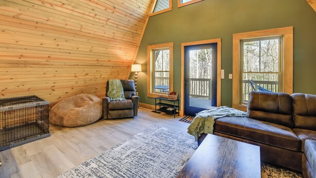 A cozy room with a sloped ceiling, wooden walls, and large windows.