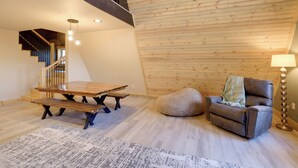 A spacious living area with a wooden ceiling, a sofa, a table, and a bench.