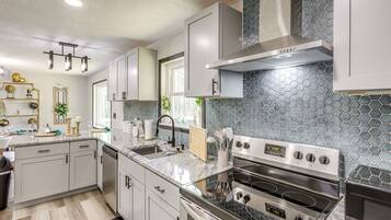 A modern kitchen with stainless steel appliances, a granite countertop, and a hexagonal tile backsplash.