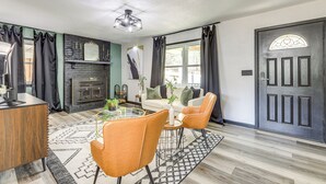 A living room with a fireplace, a dining area with a glass table, and a door with a decorative glass window.