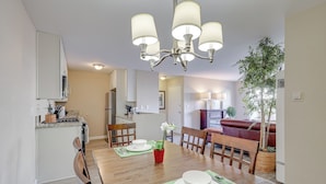 A dining area with a wooden table set for four, a chandelier, and a potted plant.