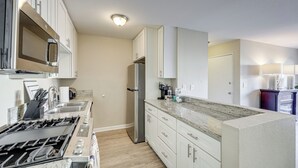 A modern kitchen with stainless steel appliances, white cabinetry, and a granite countertop.