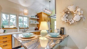 A kitchen with granite countertops, wooden cabinets, and a central island with a lamp and bowls.