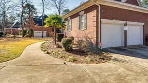 A single-story brick house with a garage, a curved driveway, and a small palm tree. - Executive Wfh-friendly Haven in Blythewood! (Blythewood)