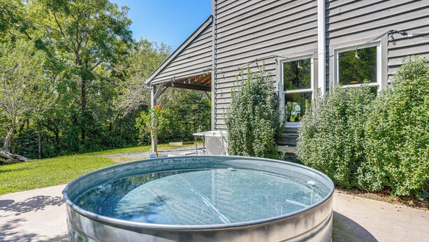 A swimming pool in front of a house with a covered patio. - Countryside Barndominium in Virginia w/ Patio (Louisa)