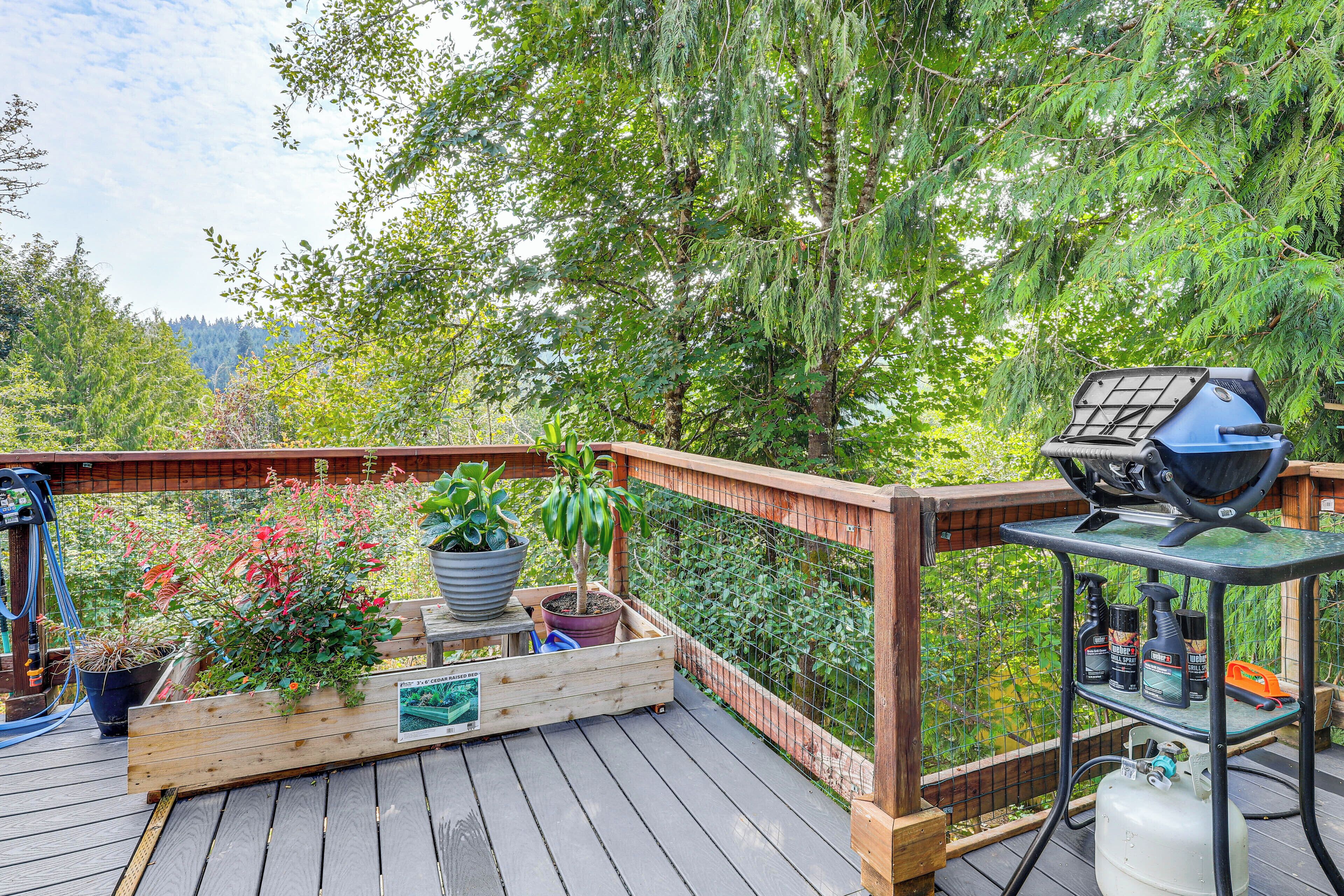 Une terrasse en bois avec un barbecue, des plantes en pot et des outils de jardinage.