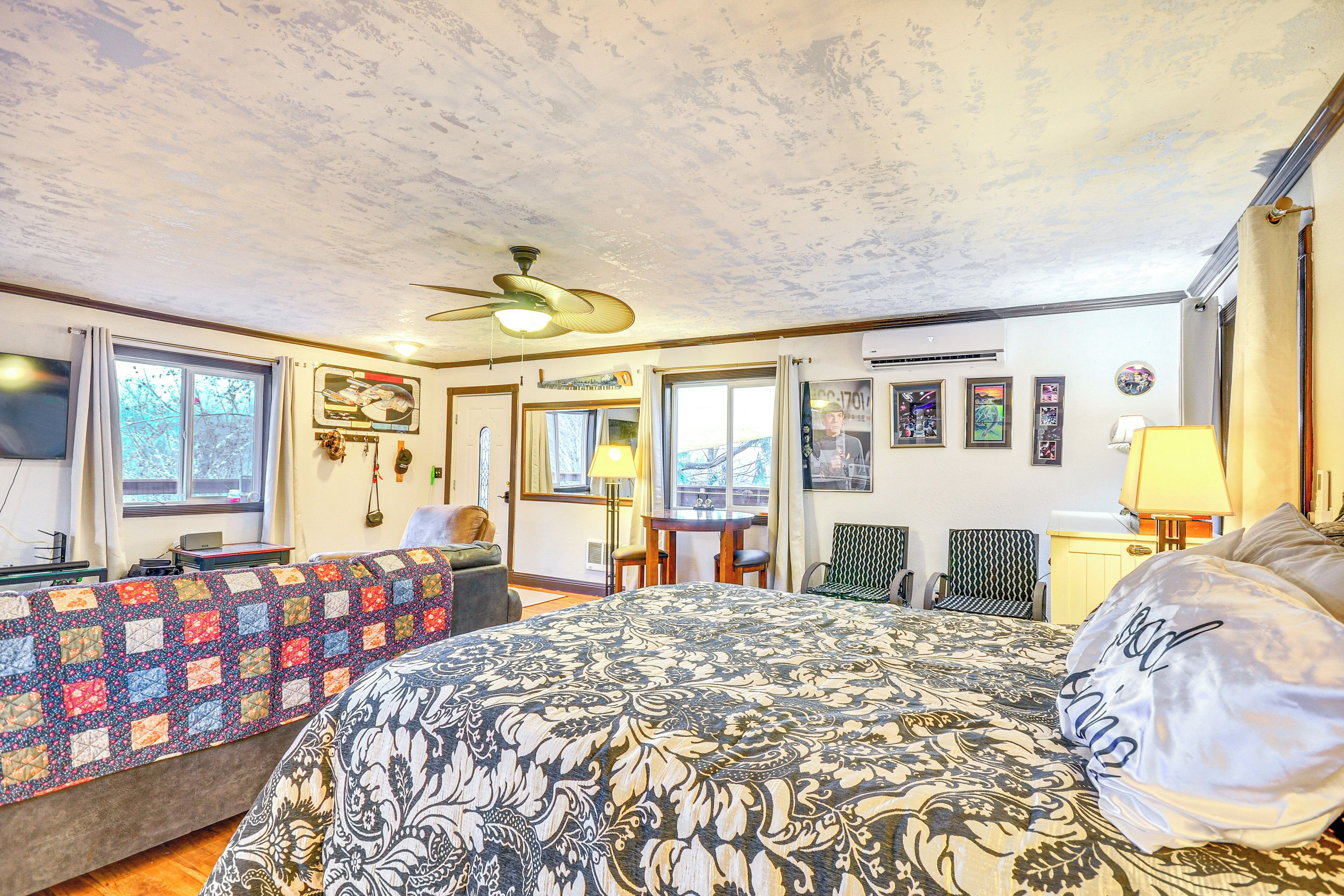 A hotel room with a large bed, a desk, a chair, and a ceiling fan.