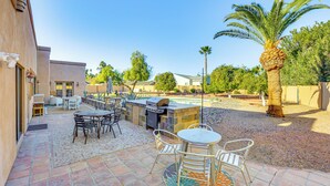 Eine Terrrasse im Freien mit Grillplatz, Sitzgelegenheiten und einem Pool.