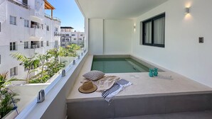 Un balcon avec une petite piscine, des murs blancs et une vue sur les bâtiments voisins.