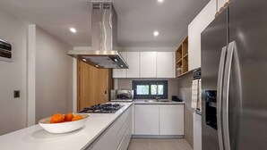 A modern kitchen with a stainless steel refrigerator, a gas stove, and a bowl of oranges on the counter. - Spectacular Brand new Beach Condo (Punta Cana)