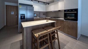 A modern kitchen with a central island, stainless steel appliances, and wooden accents. - Spectacular Golf Front 3BR Apartment! (Punta Cana)
