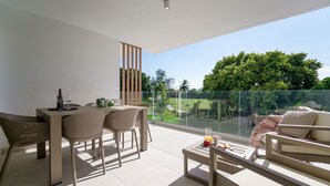 A modern outdoor living area with a dining table, chairs, and a sofa. - Spectacular Golf Front 3BR Apartment! (Punta Cana)