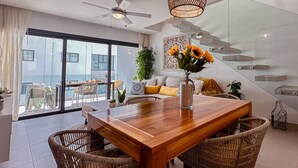 Een eethoek met een houten tafel, rieten stoelen en een vaas met bloemen.