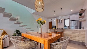 Een moderne keuken met een eetgedeelte, met een houten tafel en rieten stoelen.