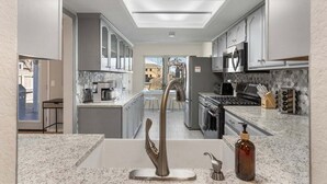 A modern kitchen with a central island, stainless steel appliances, and a view into the dining area. - South Tulsa Splash W/Pool & Hot Tub (Tulsa)