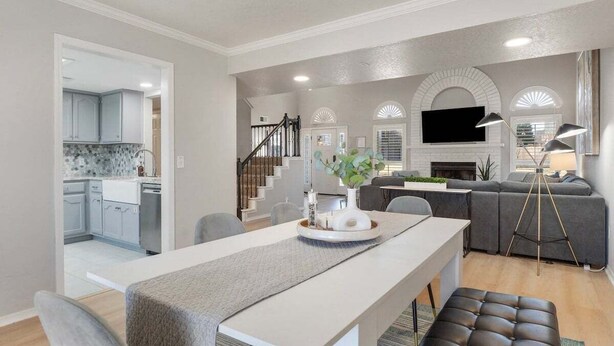 A modern living room with a dining area, a kitchen in the background, and a staircase leading to another level. - South Tulsa Splash W/Pool & Hot Tub (Tulsa)