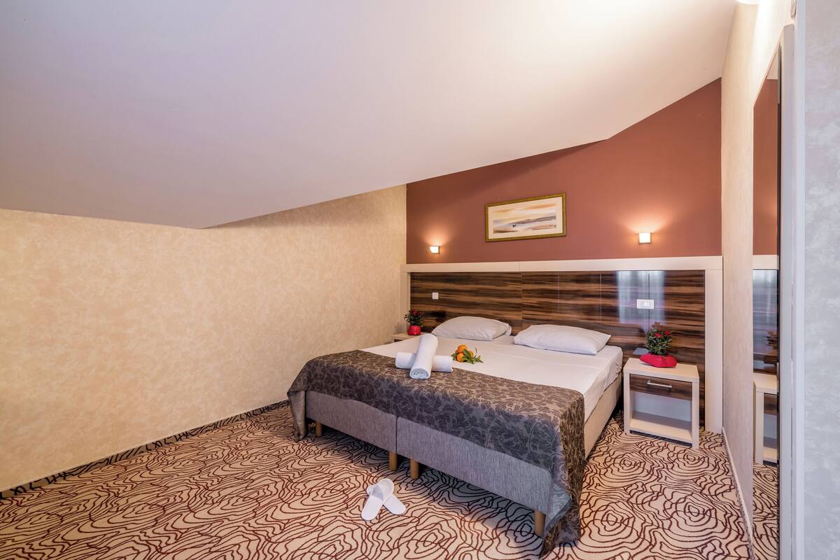 A hotel room with a bed, nightstand, and a wall-mounted light fixture.