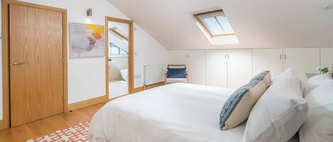 Ein Schlafzimmer mit einem großen Bett, einem Oberlicht, einem Holzschrank und einer Heizung.