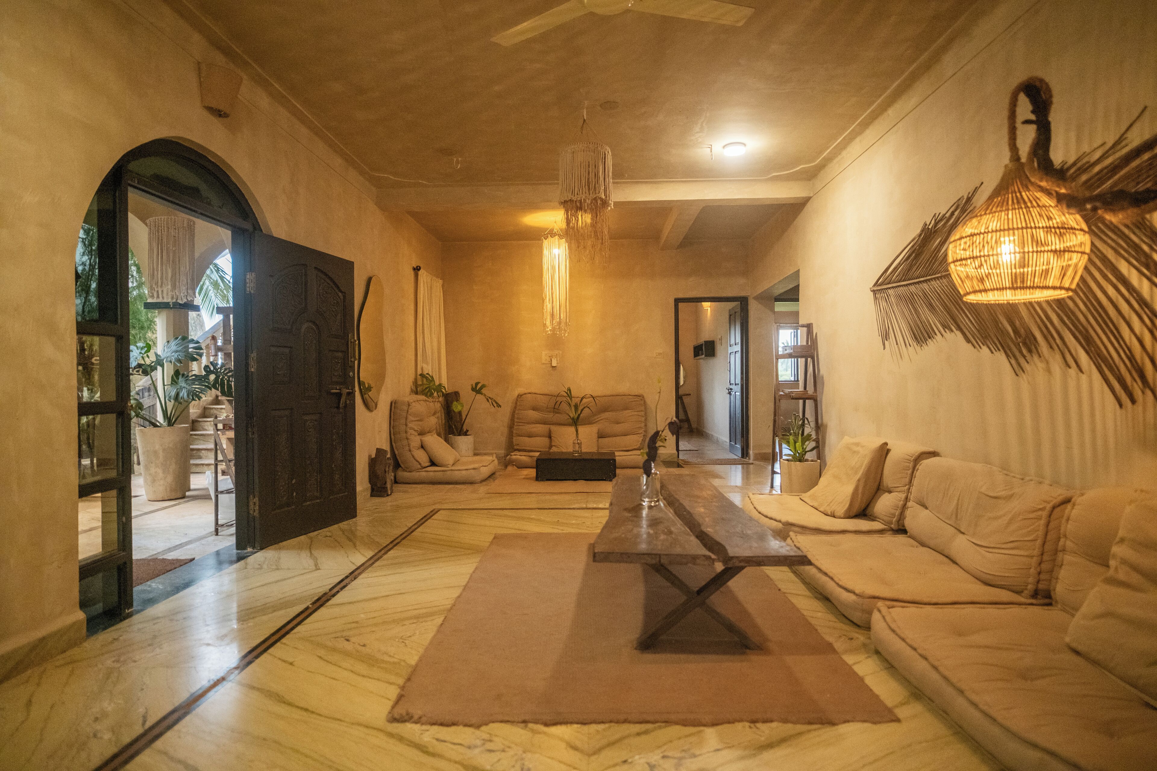 A spacious living room with a large sofa set, a wooden coffee table, and a hanging light fixture.
