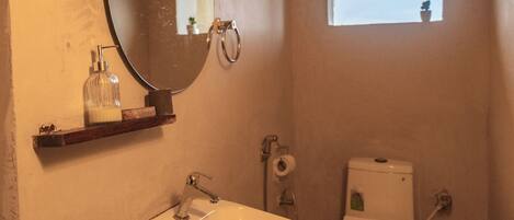 Un baño con lavamanos, inodoro y una ventana pequeña.