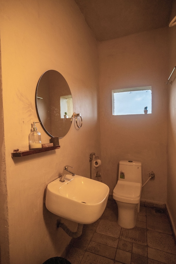 A bathroom with a sink, toilet, and a small window.