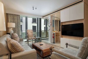 A modern living room with a sofa, armchair, coffee table, and a flat-screen TV.