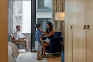 Una habitación de hotel con cama, sillón, sofá, escritorio y lámpara.