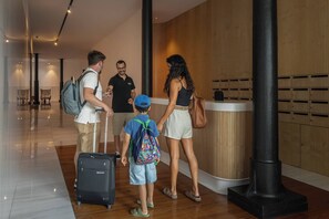 A hotel lobby with a reception desk, wooden paneling, and a luggage trolley. - Luxury Rooftop Jacuzzi Penthouse at Savoy Insular (Funchal)