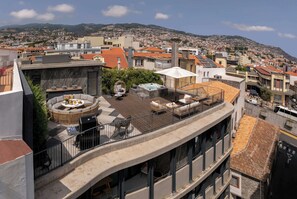 Una terraza en la azotea con mobiliario exterior, un jacuzzi y vistas a un paisaje urbano.