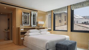 A modern bedroom with a large bed, bedside tables, and a view of the city through large windows.