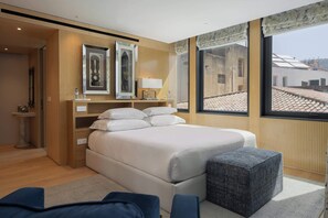Quarto moderno com uma cama grande, mesas de cabeceira e vista da cidade através de amplas janelas.
