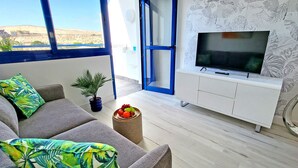 A modern living room with a sofa, a TV, a small table with fruit, and a potted plant. - Vacation apartment Costa Sun, Costa Calma, pool, WiFi, balcony (Costa Calma)