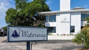 Un letrero del hotel 'The Waterway' con un edificio blanco moderno al fondo.