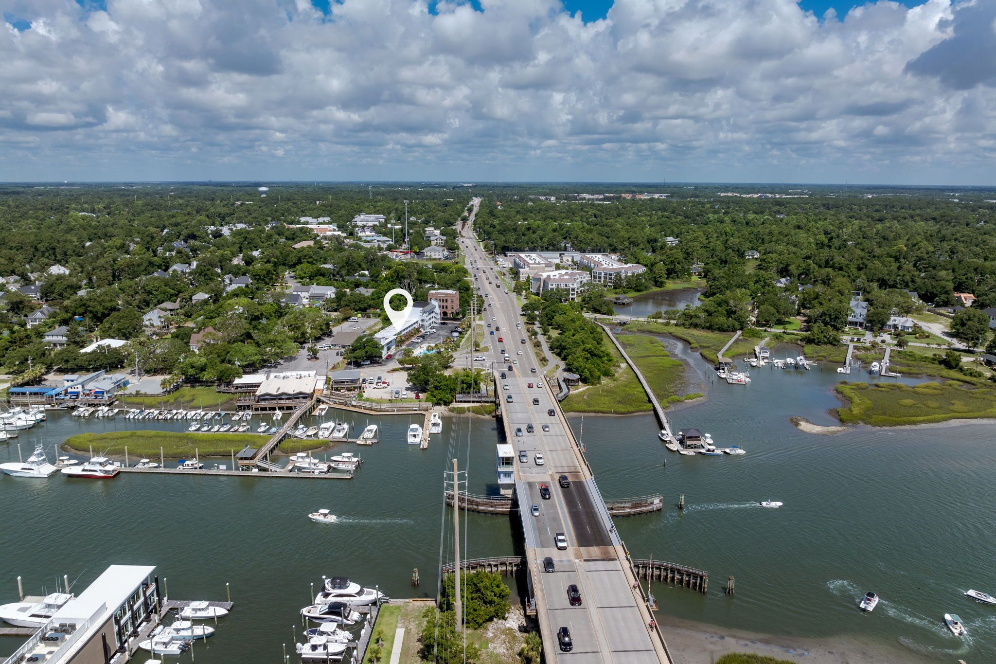 A bridge connecting two land masses over a body of water with boats docked nearby.