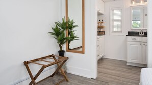Una cocina moderna con armarios blancos, un espejo con marco de madera y un helecho en maceta.